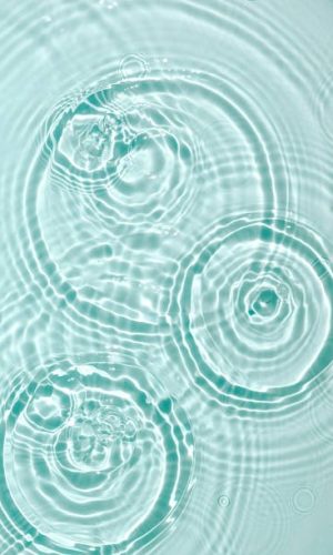 Water background. Blue water texture, blue mint water surface with rings and ripples. Spa concept background. Flat lay, top view, copy space.